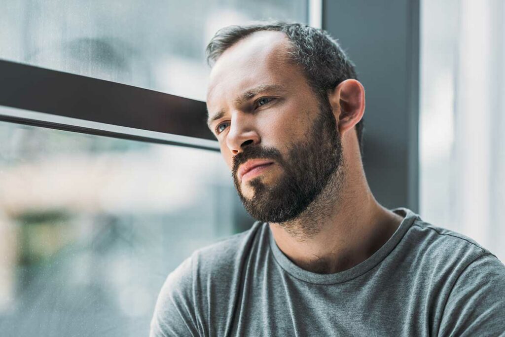 man looks out window and considers what is major depressive disorder