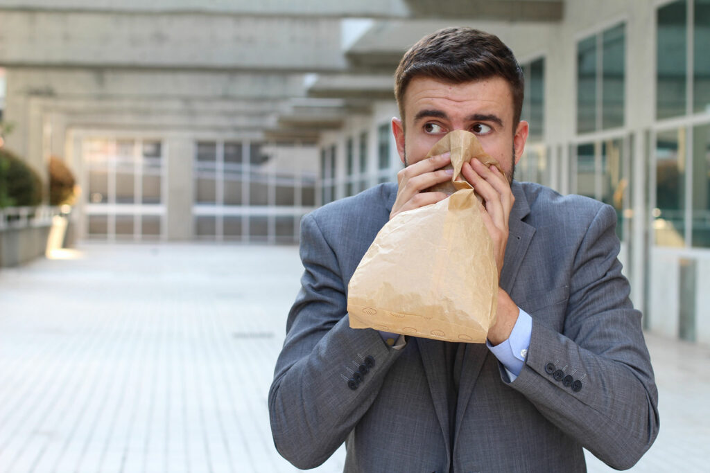 man breathes into a bag while wondering what is an anxiety attack