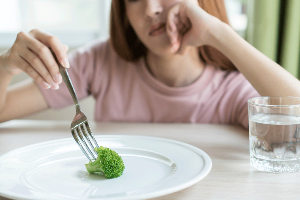 woman eating broccoli considers the types of anorexia