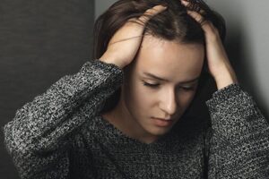 woman with hands on her head considers an anxiety treatment program