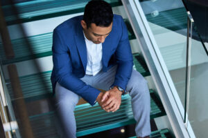 man sits on stairs and considers major depressive disorder vs chronic depression