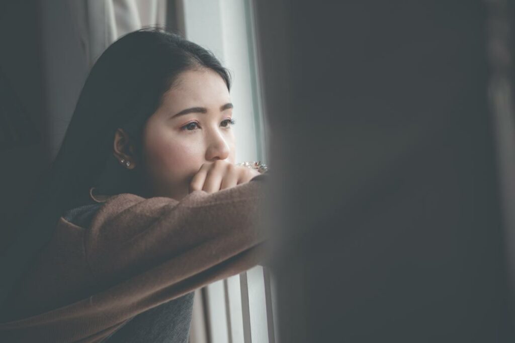 a teen looks out a window thinking about teen self harming