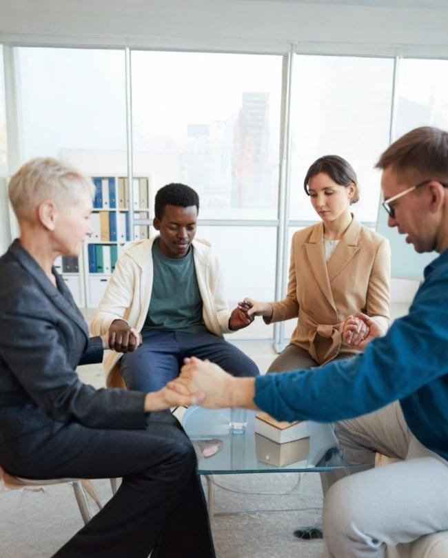 A group of people holding hands during a meditation in therapy.