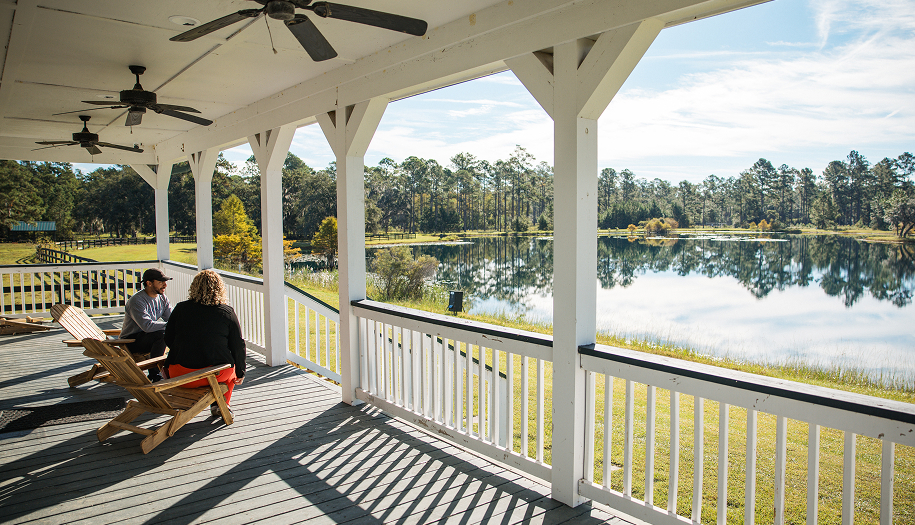 Two people on a porch looking at a scenic lake view.